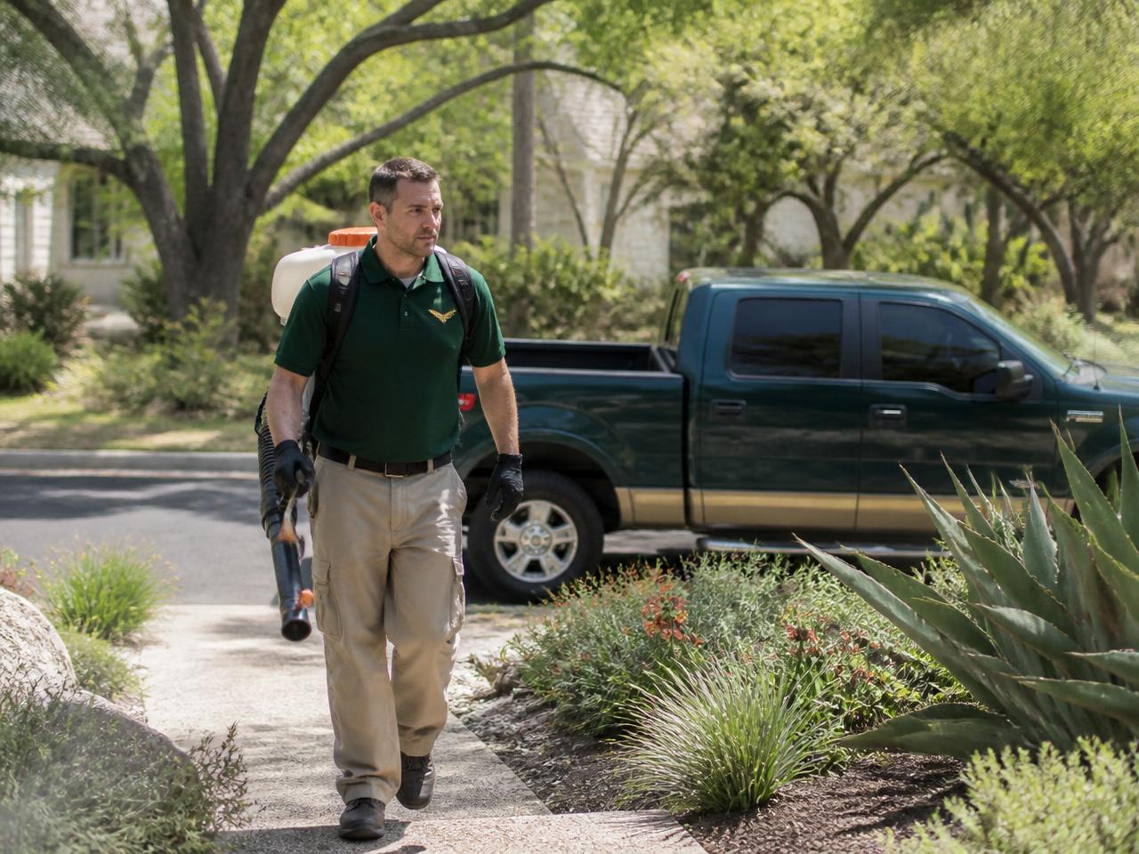 Licensed technician arriving with backpack mist blower and branded service truck